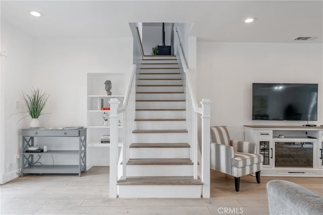 stairway with visible vents, wood finished floors, and recessed lighting