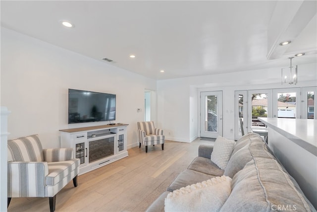 living area featuring a fireplace, light wood-style floors, french doors, and recessed lighting