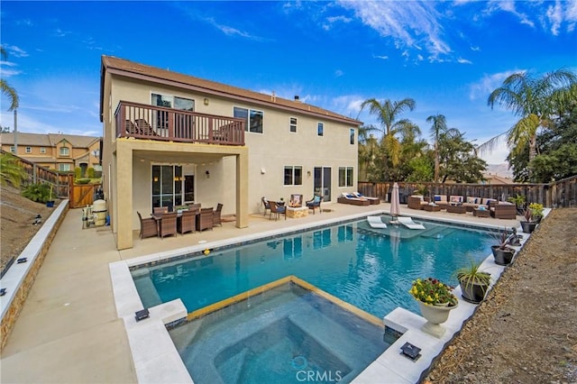 back of house with a pool with hot tub, an outdoor living space with a fire pit, a patio, and a balcony