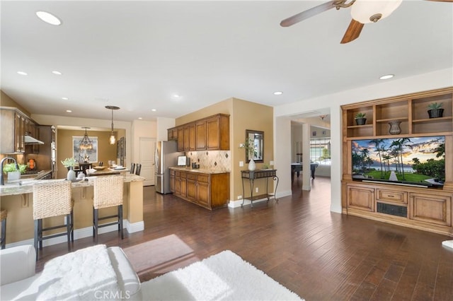 kitchen with tasteful backsplash, dark hardwood / wood-style floors, pendant lighting, and a kitchen breakfast bar