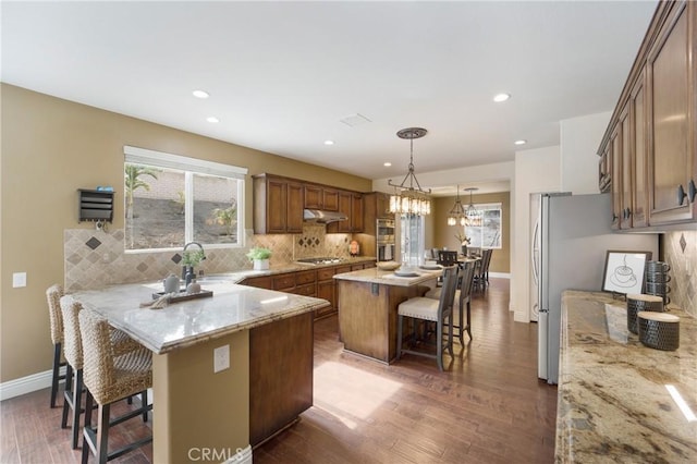 kitchen featuring a kitchen island, tasteful backsplash, a breakfast bar area, hanging light fixtures, and stainless steel appliances