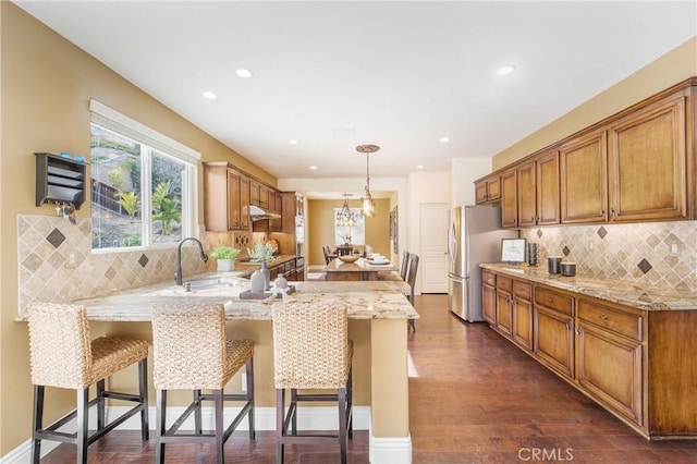 kitchen featuring pendant lighting, a breakfast bar area, stainless steel fridge, and kitchen peninsula