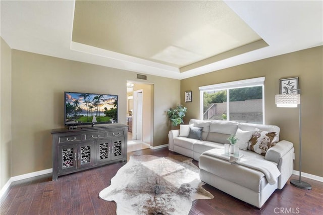 living room with dark wood-type flooring and a raised ceiling