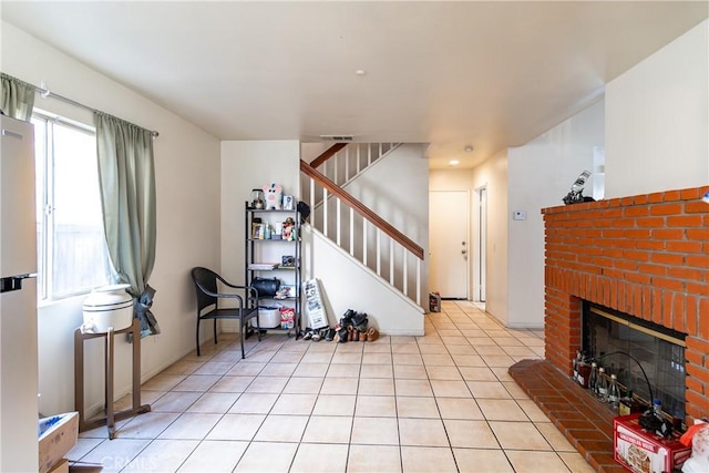 living room with a brick fireplace and light tile patterned floors