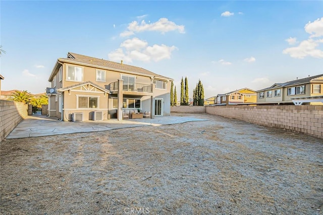 back of property with a balcony, a patio area, and central air condition unit