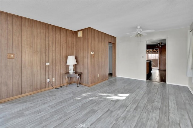 spare room with hardwood / wood-style flooring, wooden walls, and ceiling fan