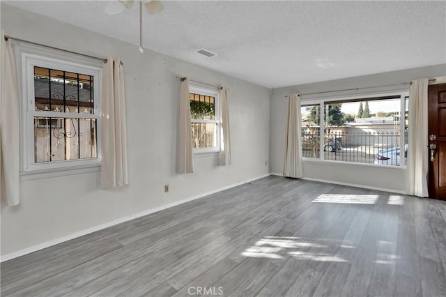 unfurnished room with wood-type flooring and a textured ceiling