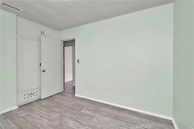 unfurnished bedroom featuring a closet, a textured ceiling, and light hardwood / wood-style flooring