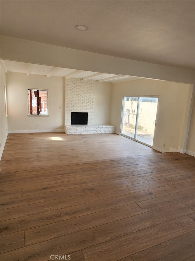 unfurnished living room with beamed ceiling, plenty of natural light, and dark hardwood / wood-style floors