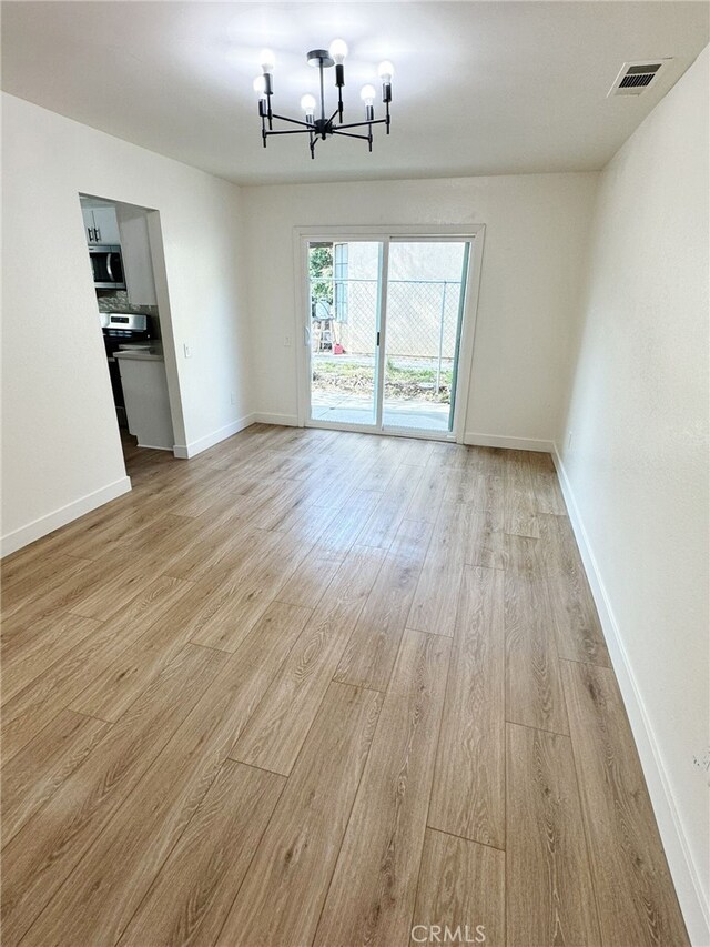 unfurnished dining area featuring light hardwood / wood-style floors and a notable chandelier