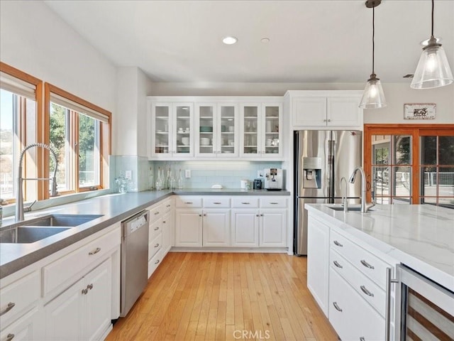 kitchen featuring beverage cooler, a sink, white cabinetry, appliances with stainless steel finishes, and glass insert cabinets