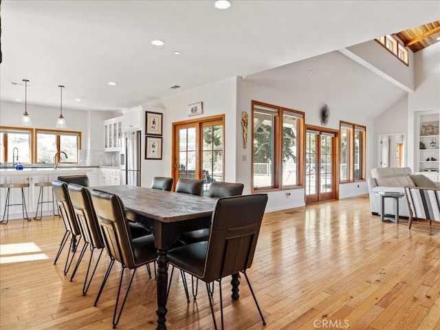 dining space with french doors, recessed lighting, light wood-style flooring, high vaulted ceiling, and baseboards