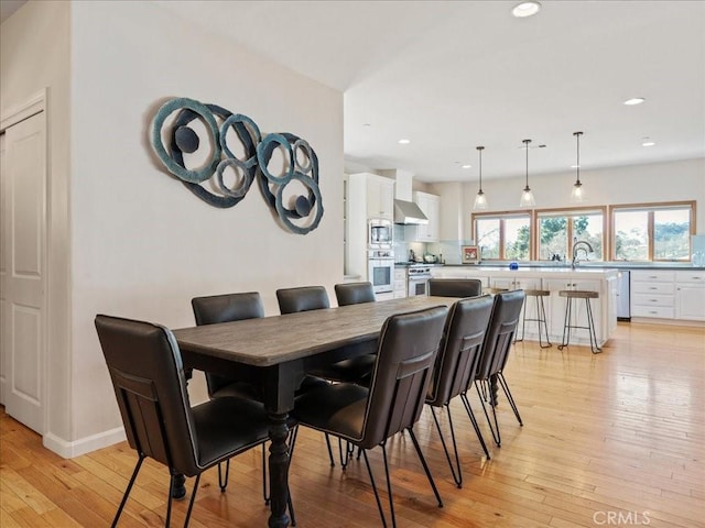 dining space featuring light wood finished floors, baseboards, and recessed lighting