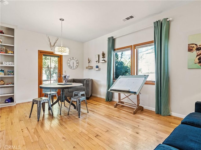 dining space with light wood finished floors, visible vents, and baseboards