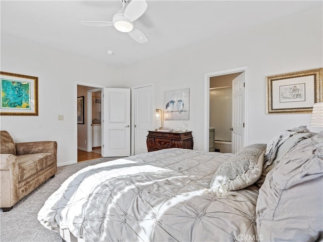 bedroom with connected bathroom, light carpet, ceiling fan, and baseboards