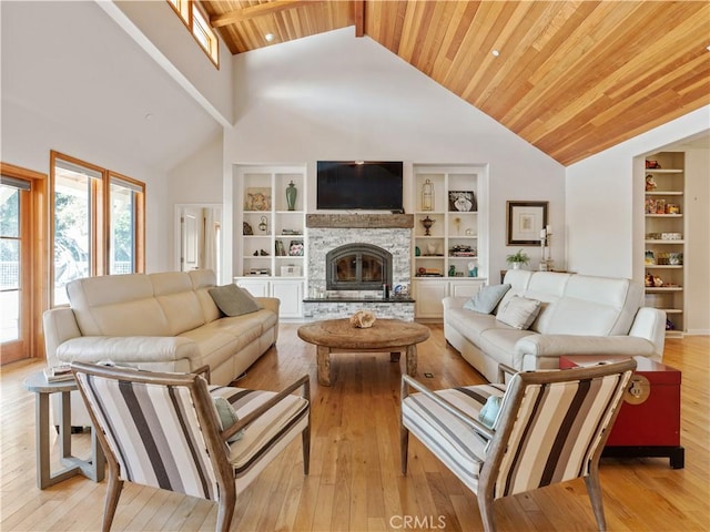 living room with light wood-type flooring, wooden ceiling, built in features, and a stone fireplace