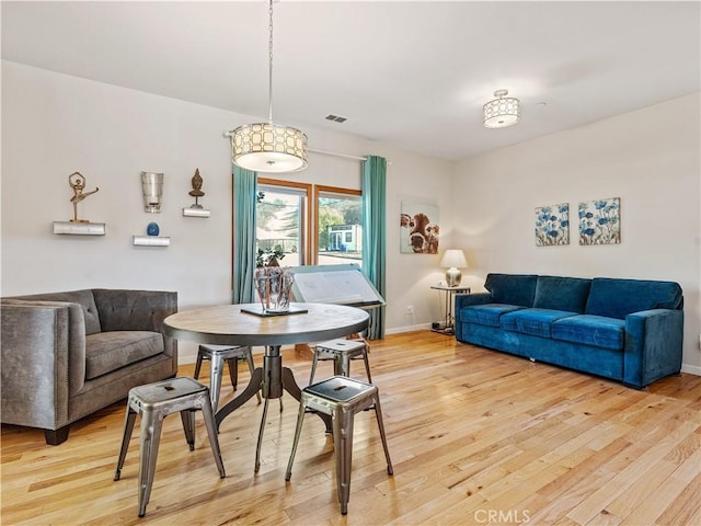 dining room with baseboards, visible vents, and wood finished floors