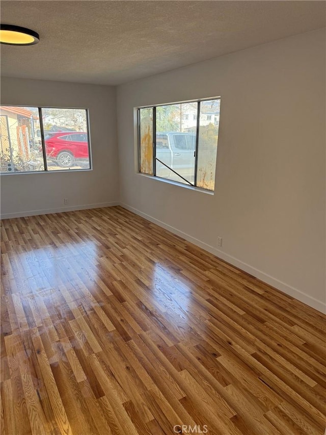 spare room featuring light hardwood / wood-style flooring and a textured ceiling