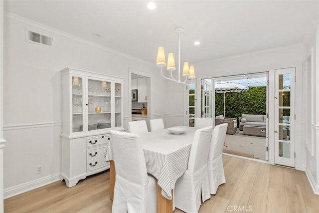 dining area featuring a notable chandelier, light hardwood / wood-style flooring, and ornamental molding