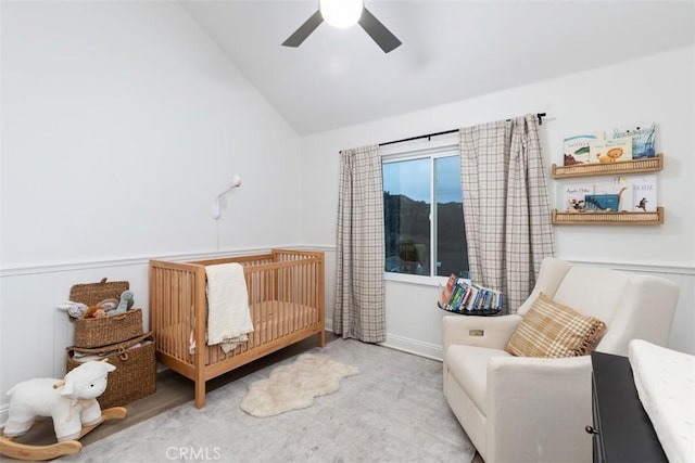 bedroom featuring a nursery area, ceiling fan, and vaulted ceiling