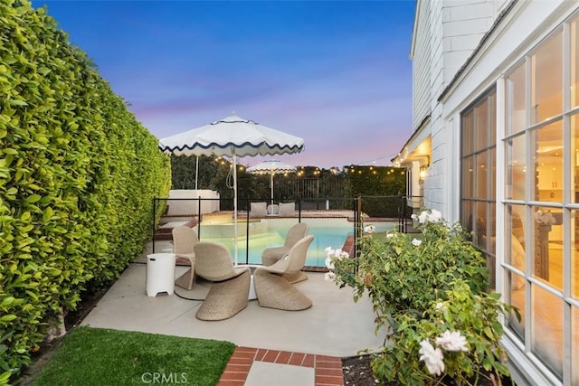 patio terrace at dusk with a fenced in pool