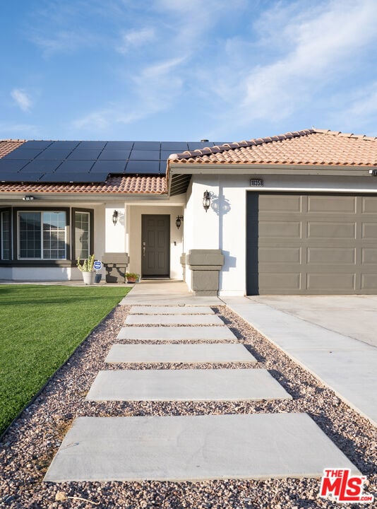 view of front facade with a garage, a front lawn, and solar panels