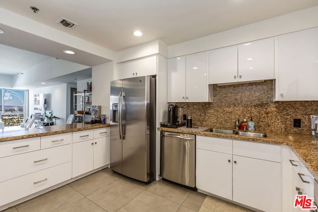 kitchen featuring stone counters, appliances with stainless steel finishes, tasteful backsplash, sink, and white cabinets