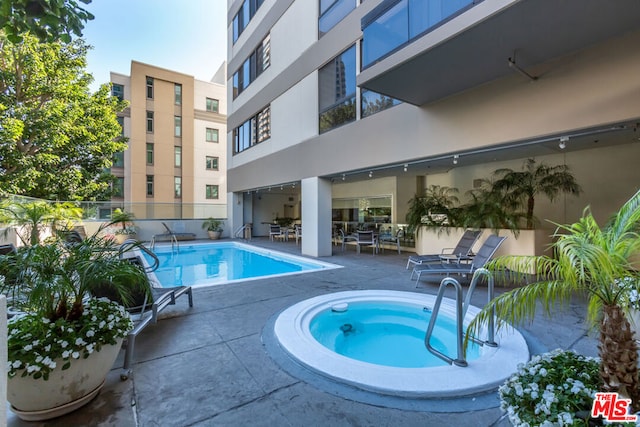 view of swimming pool featuring a hot tub and a patio