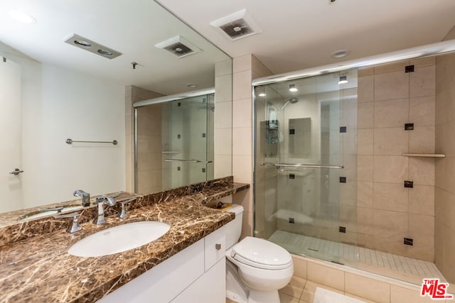 bathroom featuring vanity, a shower with shower door, and toilet