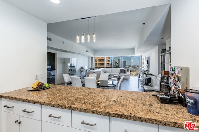 kitchen featuring decorative light fixtures, wood-type flooring, dark stone counters, and white cabinets