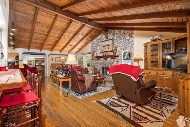 living room featuring hardwood / wood-style floors, a stone fireplace, and lofted ceiling with beams