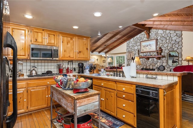 kitchen featuring appliances with stainless steel finishes, tile countertops, vaulted ceiling with beams, backsplash, and light wood-type flooring