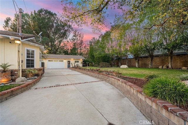 yard at dusk featuring a garage