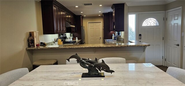 kitchen with light stone counters, sink, a breakfast bar, and kitchen peninsula