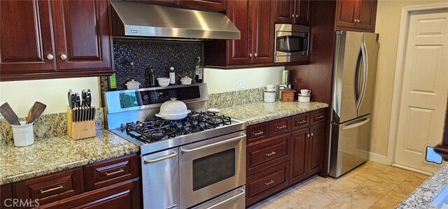 kitchen with light stone countertops, range hood, and appliances with stainless steel finishes