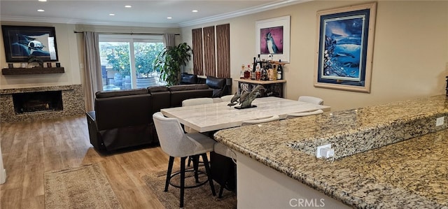 dining area featuring ornamental molding, a high end fireplace, and light hardwood / wood-style flooring