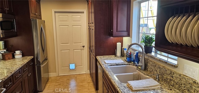 kitchen with stainless steel appliances, sink, and light stone counters