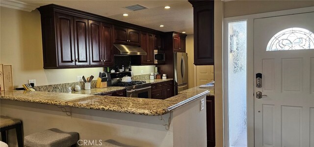 kitchen with light stone counters, a kitchen breakfast bar, kitchen peninsula, and appliances with stainless steel finishes