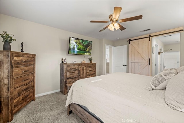 bedroom featuring ceiling fan, light colored carpet, and a barn door