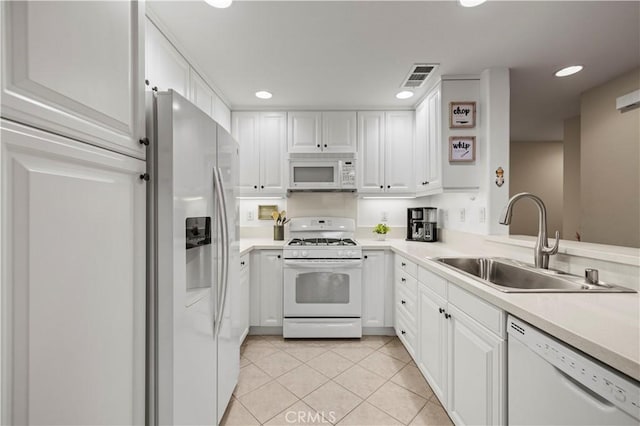 kitchen with white appliances, light countertops, a sink, and white cabinets