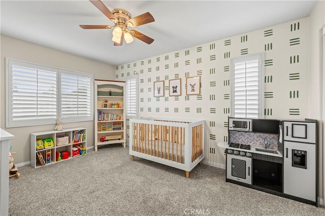 bedroom with a crib, carpet flooring, sink, and ceiling fan