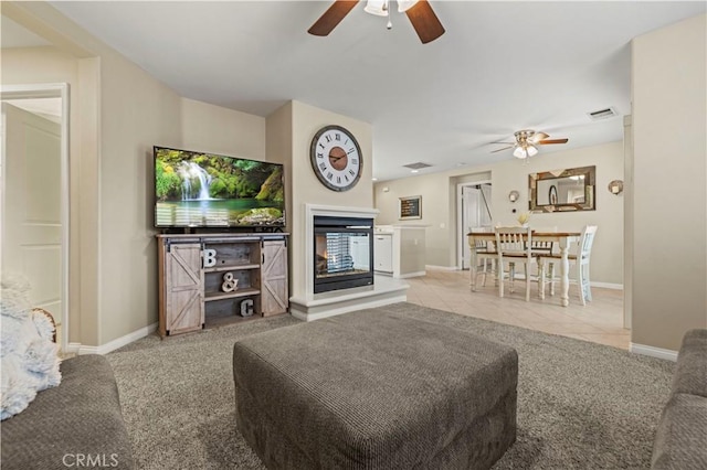 living room with light tile patterned floors, ceiling fan, and a multi sided fireplace