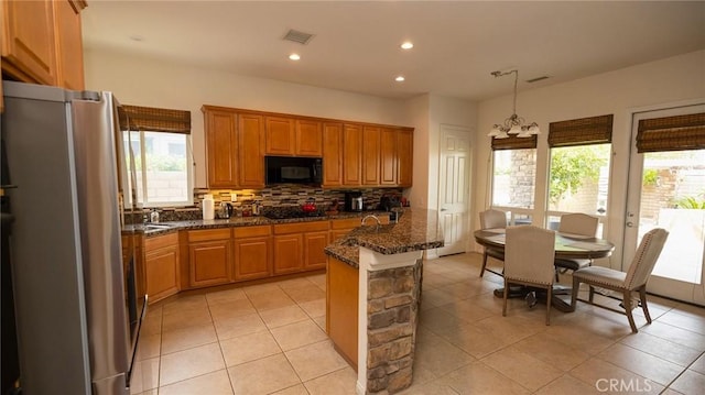 kitchen with pendant lighting, light tile patterned floors, tasteful backsplash, black appliances, and dark stone counters