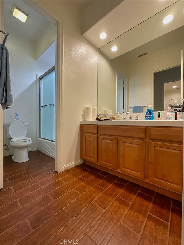 full bathroom featuring bath / shower combo with glass door, vanity, and toilet