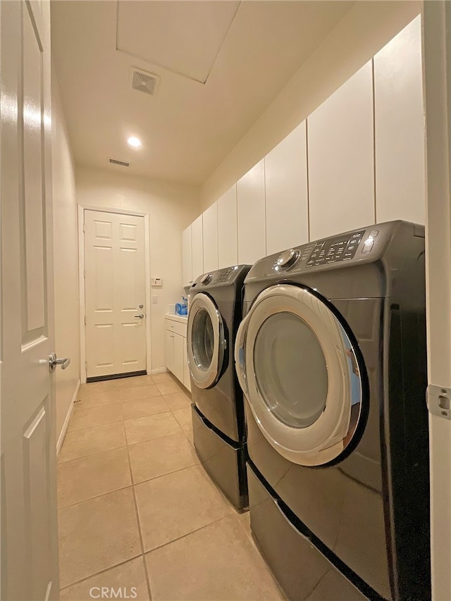 laundry area with separate washer and dryer, cabinets, and light tile patterned flooring