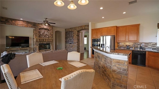 dining area featuring light tile patterned flooring, a fireplace, and ceiling fan