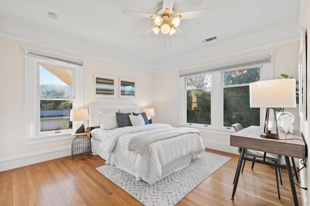 bedroom with hardwood / wood-style flooring, ceiling fan, ornamental molding, and multiple windows