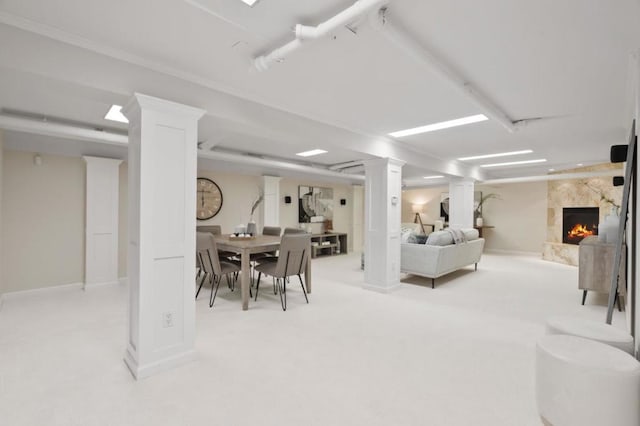 dining room with a fireplace, light carpet, and ornate columns