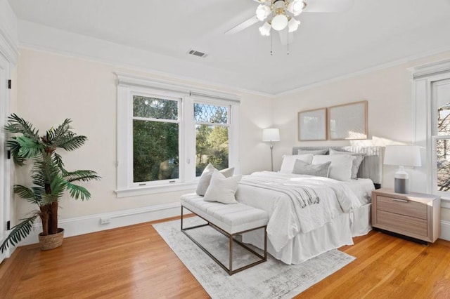 bedroom with ornamental molding, ceiling fan, and light hardwood / wood-style flooring