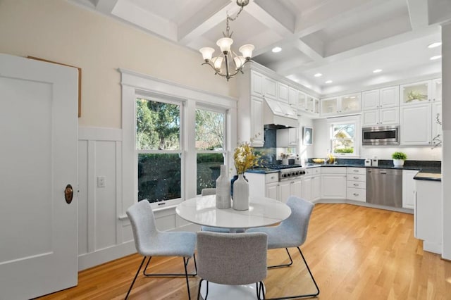 dining space with beamed ceiling, an inviting chandelier, coffered ceiling, and light hardwood / wood-style floors